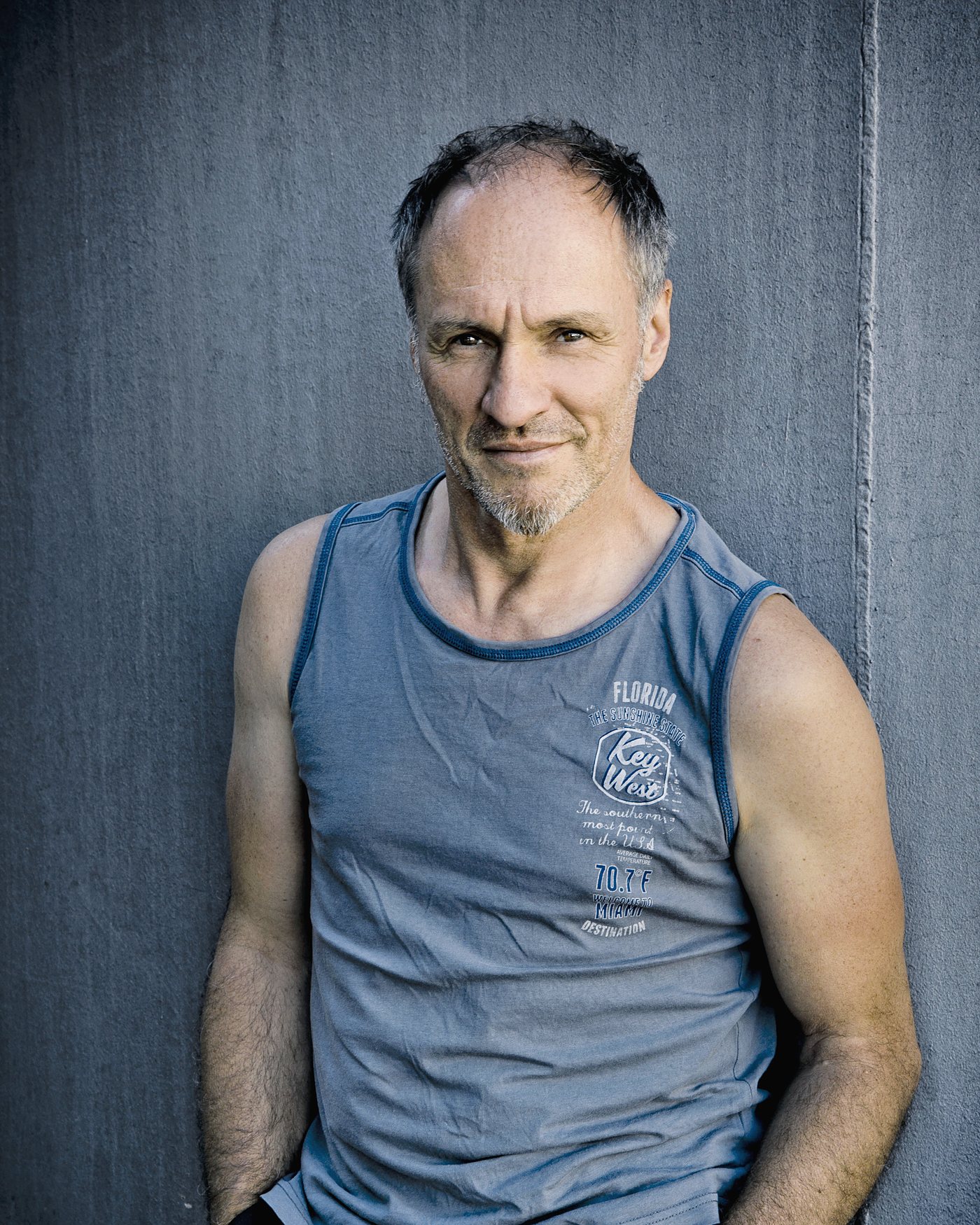 Armin Stockerer im grauen Shirt vor einer Betonwand, Hände in den Taschen – Foto: Christian Hartmann